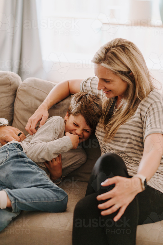 Young boy giggling while snuggling into mums side. - Australian Stock Image