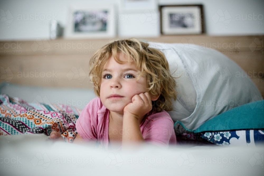 Young boy in bed in natural morning light - Australian Stock Image