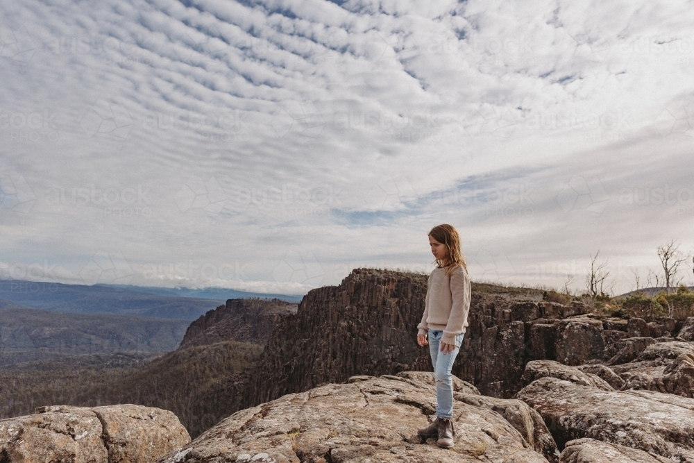 Young boy looking out from mountain over landscape - Australian Stock Image