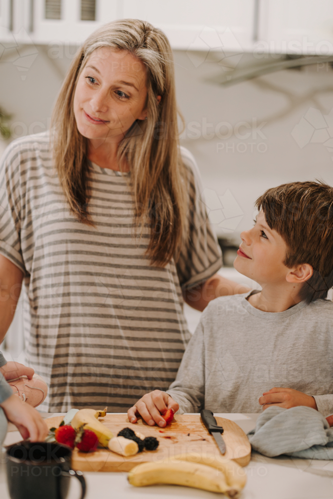 Young boy looking up to mum while holding a fruit. - Australian Stock Image
