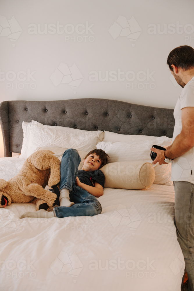 Young boy lying comfortably on a cosy bed. - Australian Stock Image