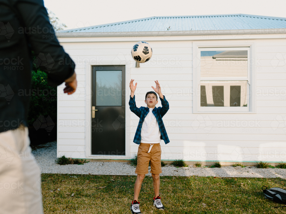 Young boy playing soccer in their yard. - Australian Stock Image