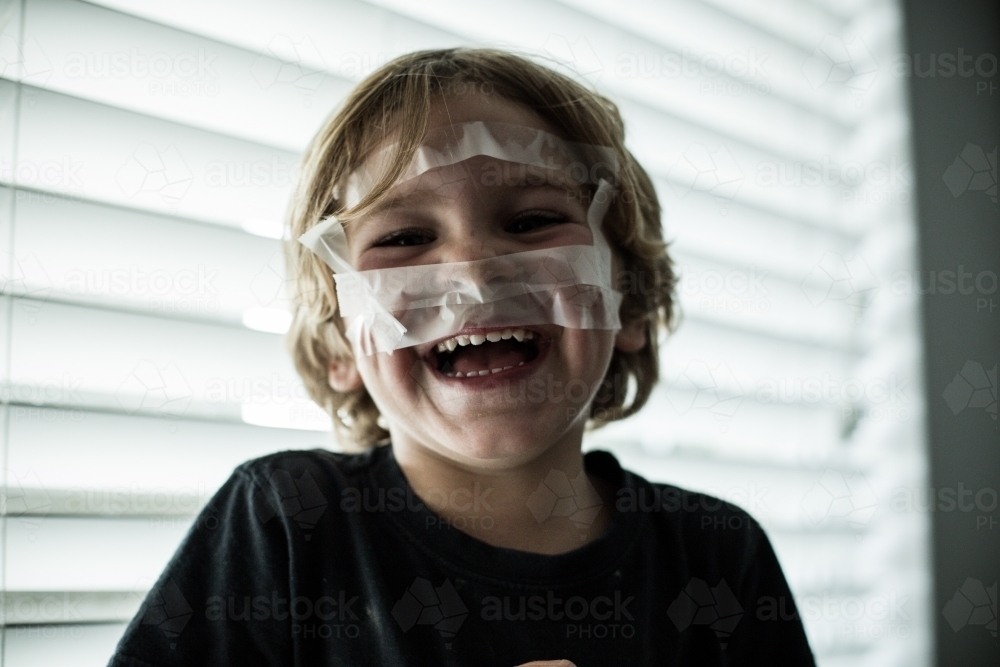 Young boy playing with sticky tape - Australian Stock Image