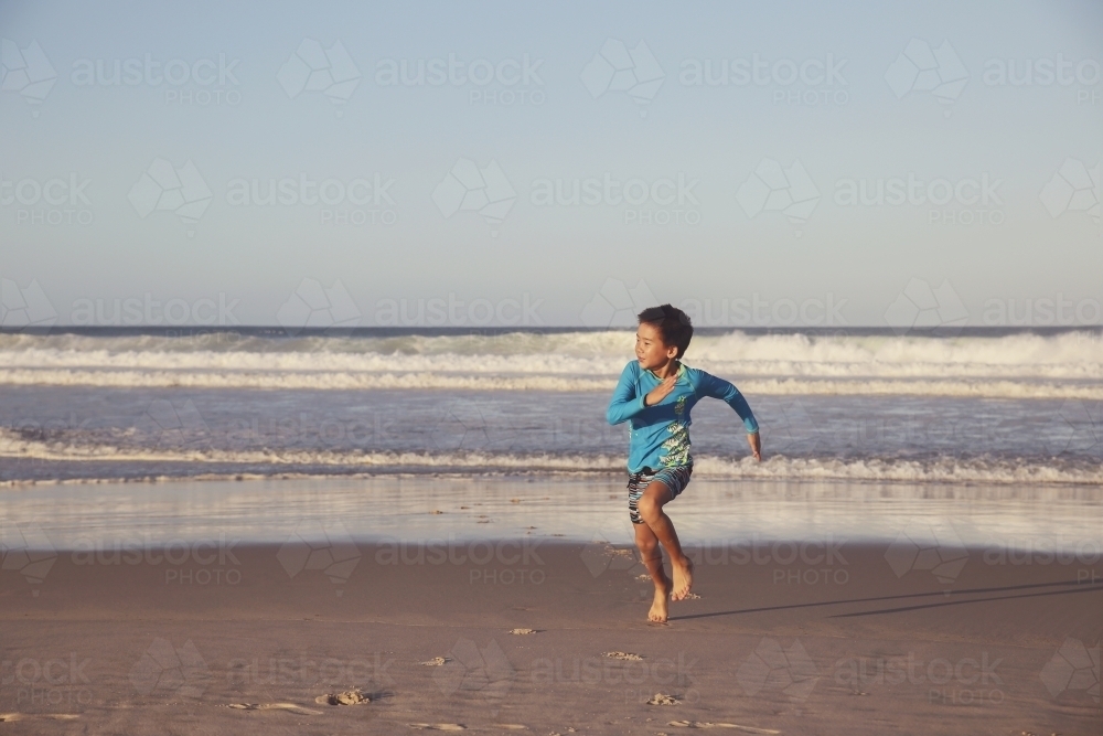 Young boy running on the beach - Australian Stock Image