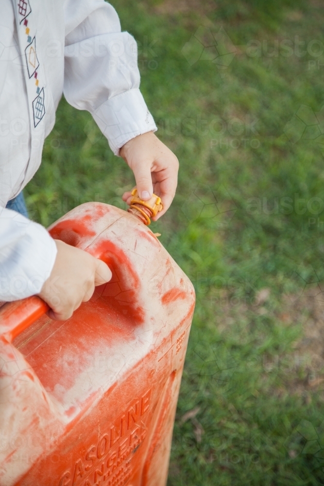 Young boy screwing lid on petrol can - Australian Stock Image