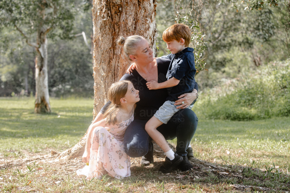 Young boy sitting mother's lap while crouching on the ground - Australian Stock Image