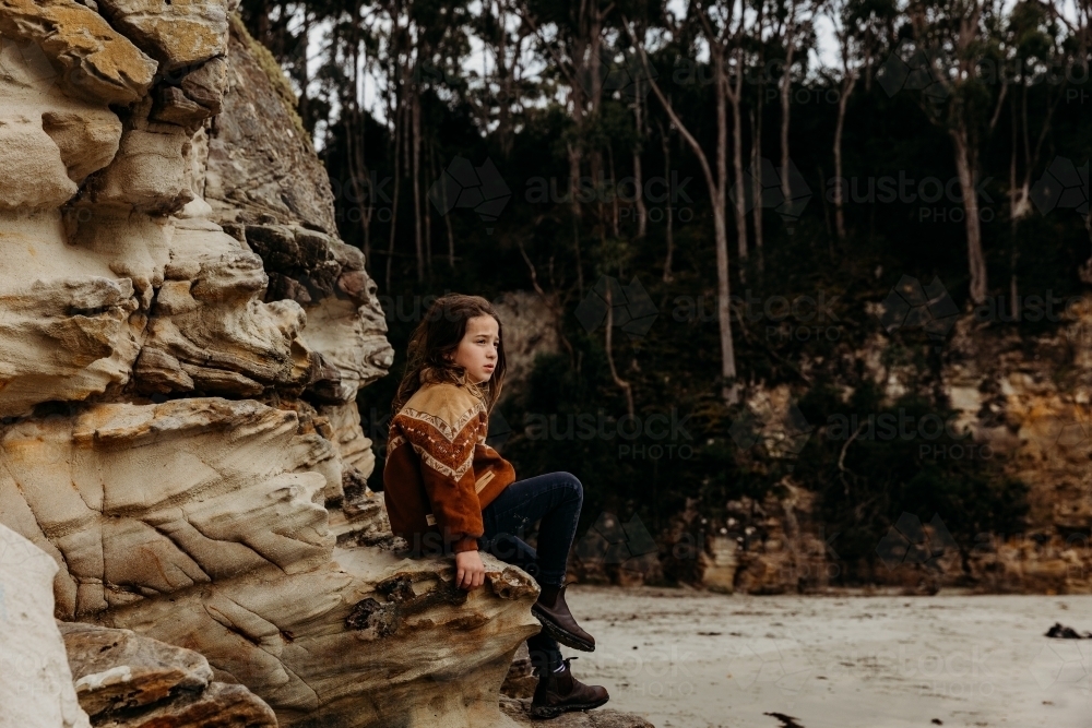 Young boy sitting on coastal rocks - Australian Stock Image