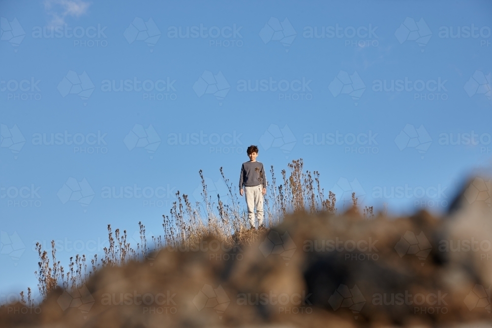 Young boy standing on hill top - Australian Stock Image