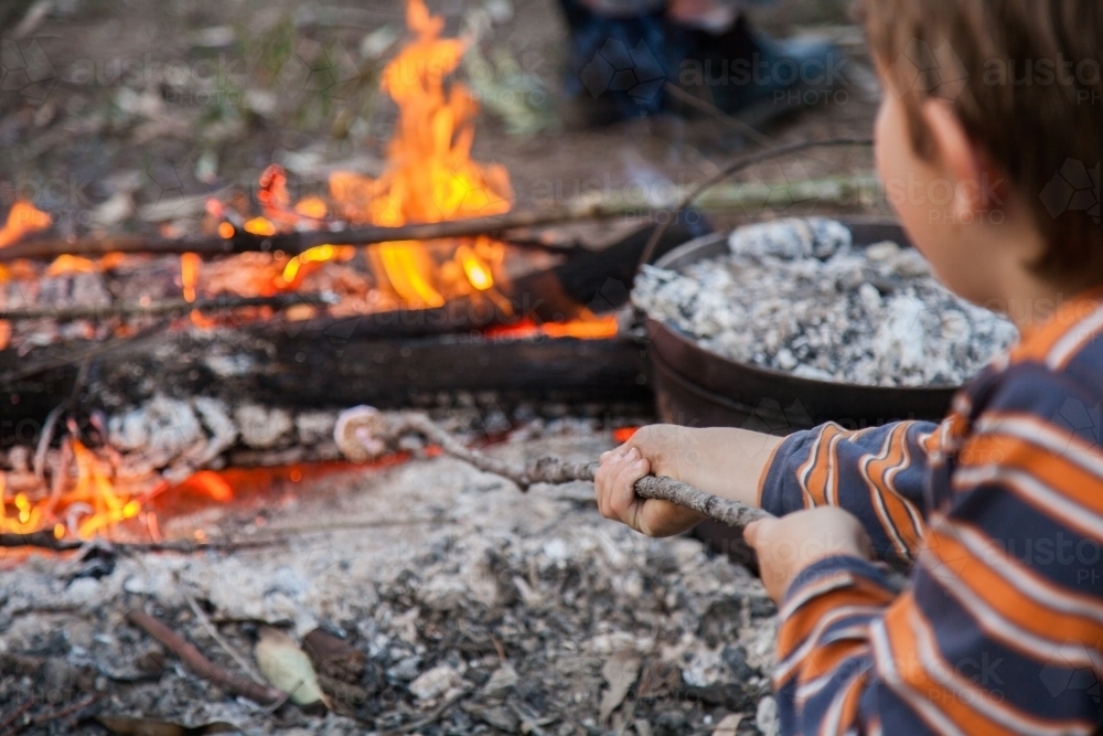 Young boy toasting a marshmallow on a campfire - Australian Stock Image