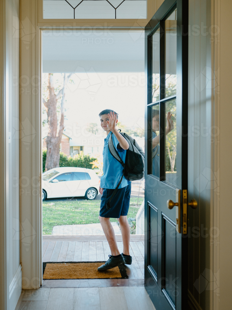 Young boy waving his hand goodbye at the doorway. - Australian Stock Image