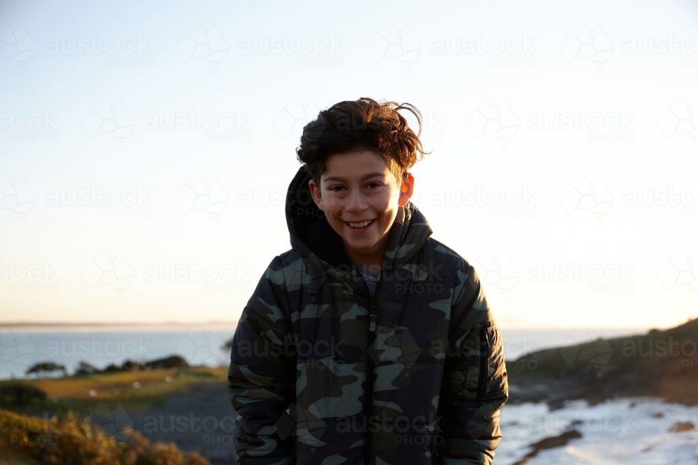 Young boy wearing camo jacket on sunrise - Australian Stock Image