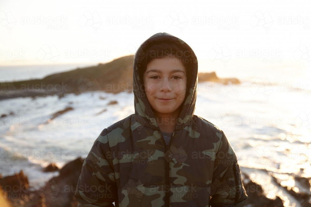 Young boy wearing camo jacket on sunrise - Australian Stock Image