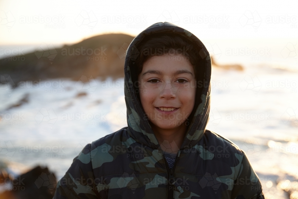 Young boy wearing camo jacket on sunrise - Australian Stock Image