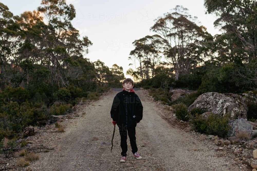 Young boy with stick on walking path - Australian Stock Image