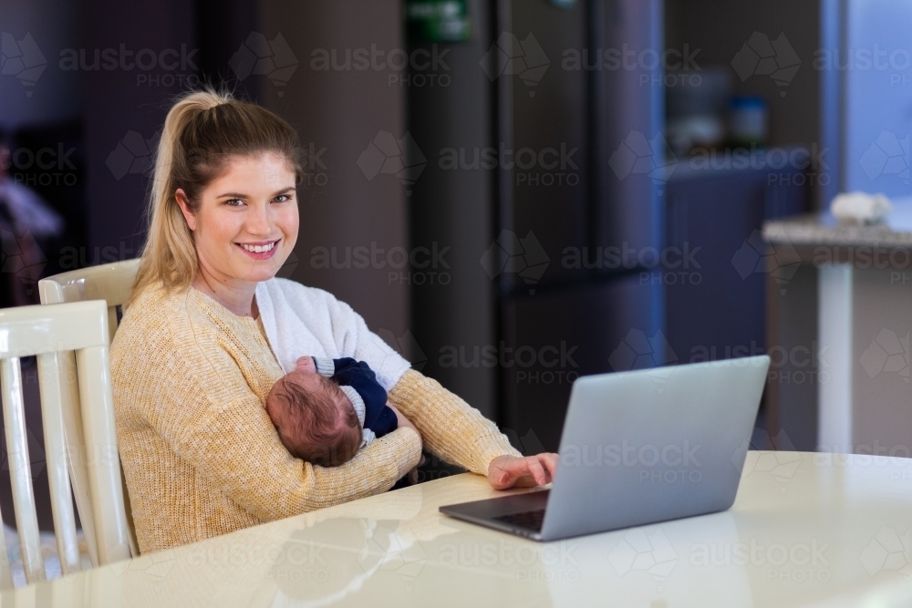 Young businesswoman mum working from home on laptop with newborn baby - Australian Stock Image