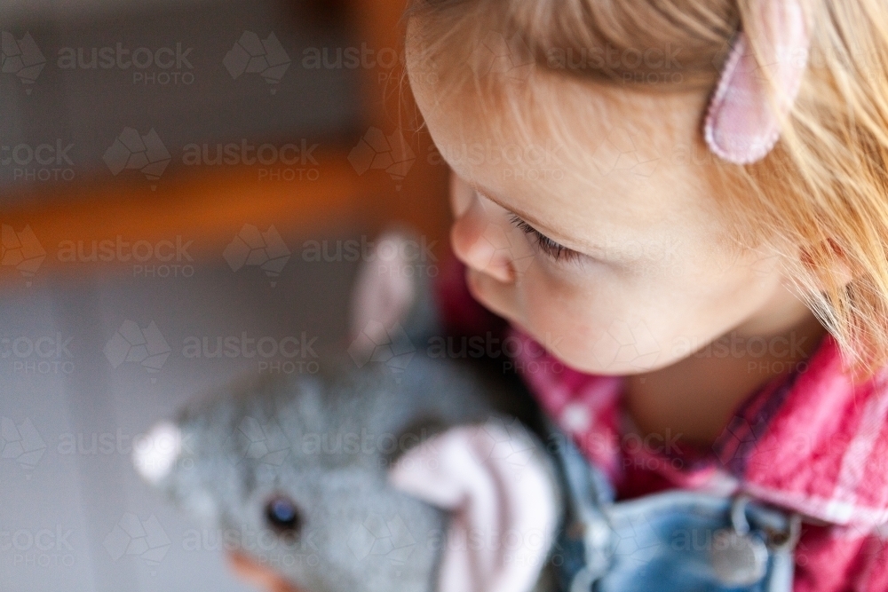 young child cuddling a plush toy possum - Australian Stock Image