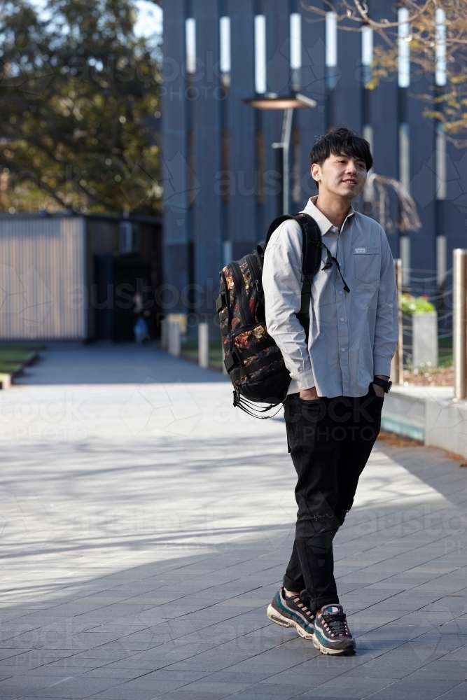 Young Chinese man smiling with backpack at university campus - Australian Stock Image