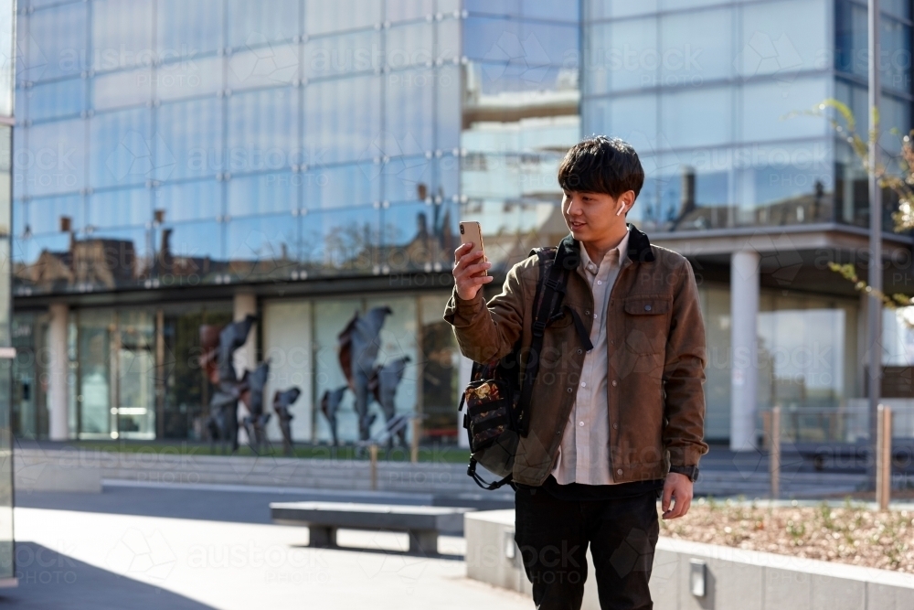 Young Chinese student outdoors with mopile phone - Australian Stock Image