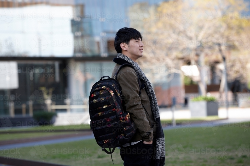 Young Chinese student outdoors with scarf and backpack - Australian Stock Image