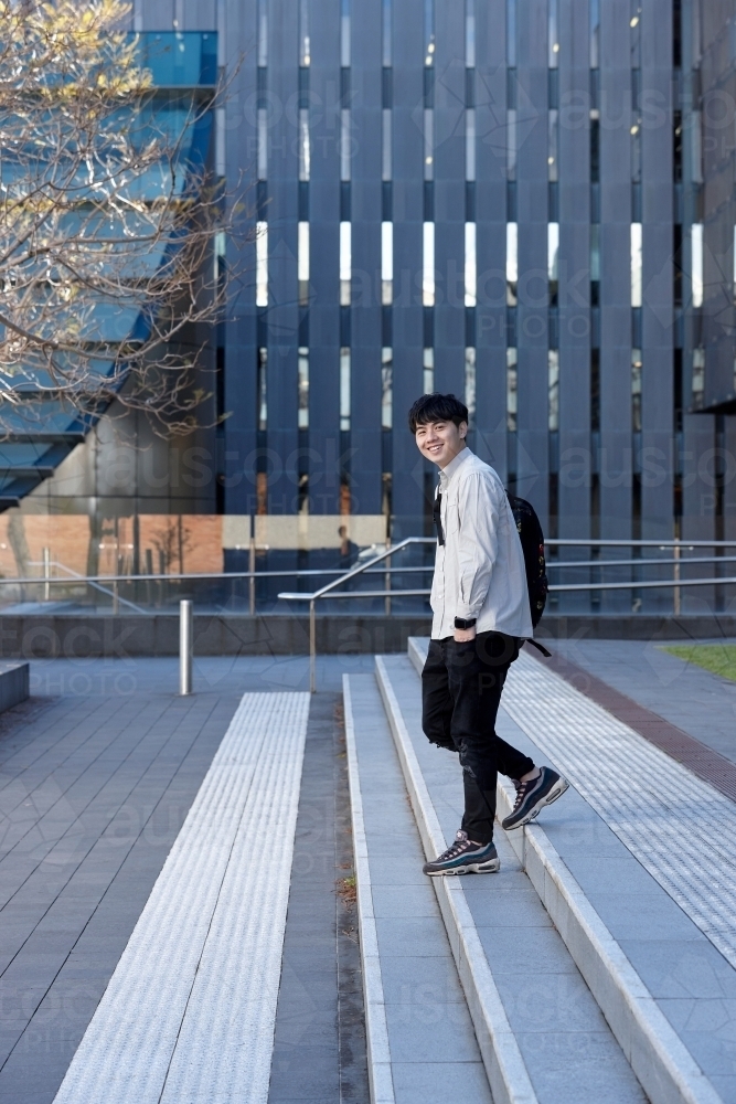 Young Chinese student walking on stairs at university campus - Australian Stock Image