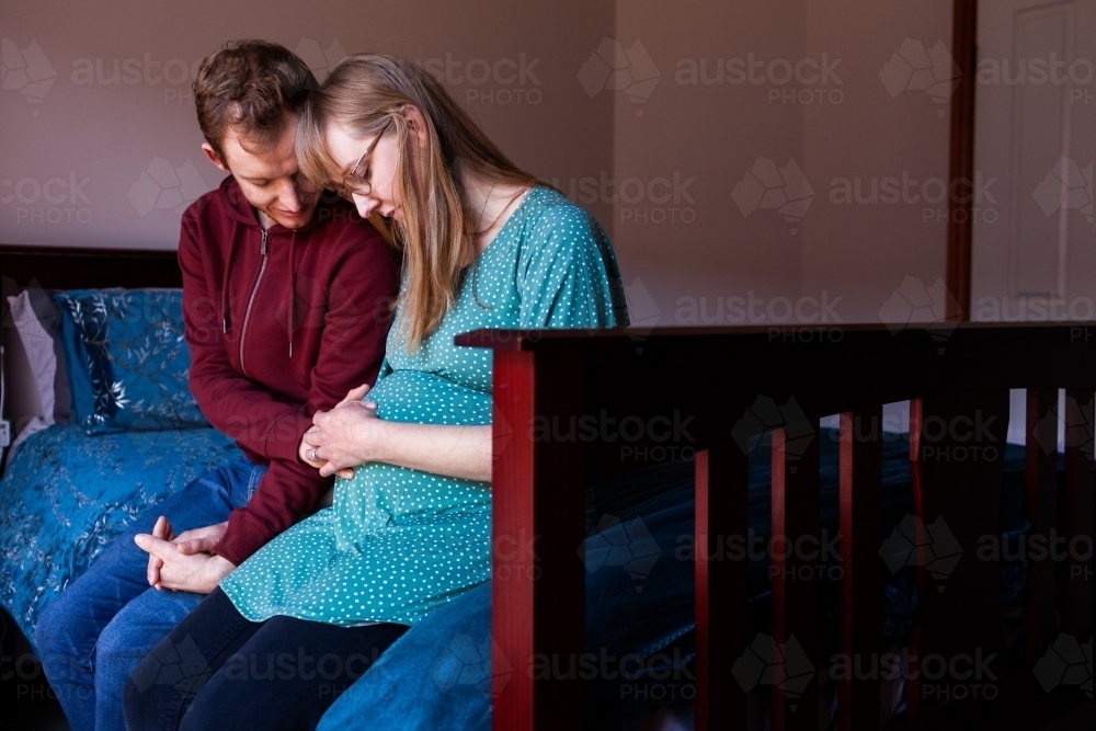 Young christian couple praying together in bedroom for unborn baby - Australian Stock Image