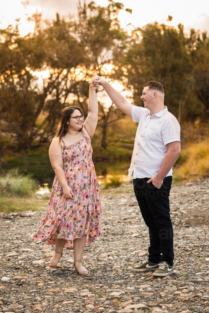 Young couple dancing by river laughing in love - Australian Stock Image