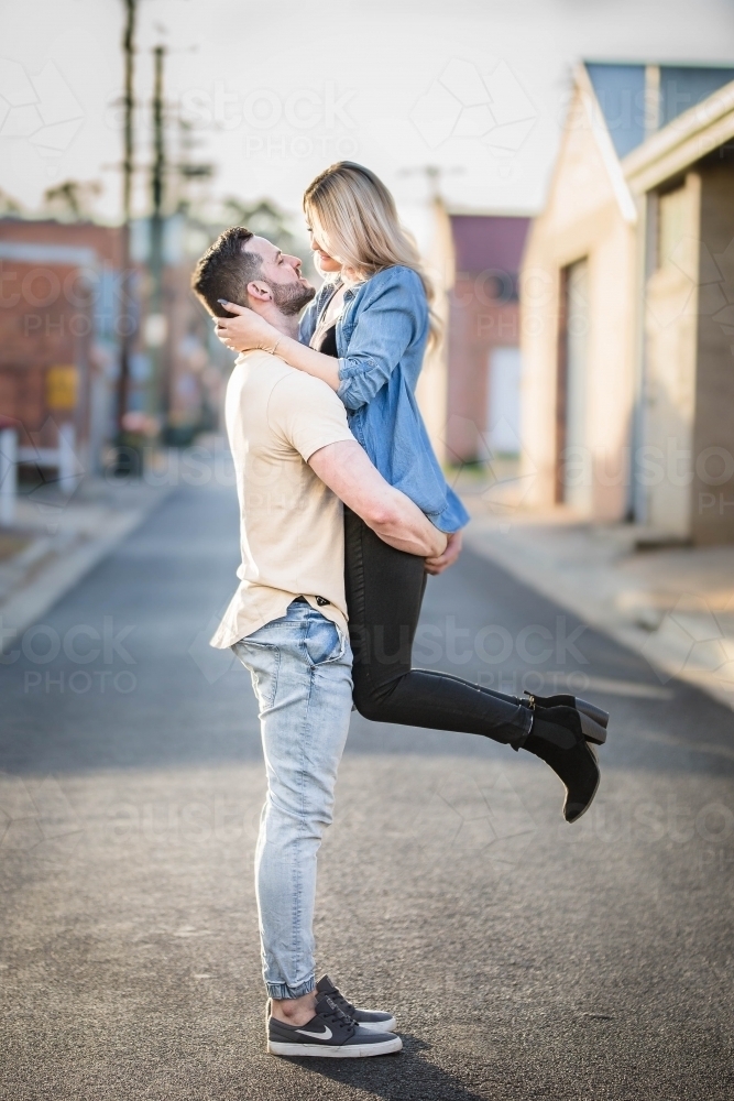 Young couple in alley way with man lifting woman - Australian Stock Image