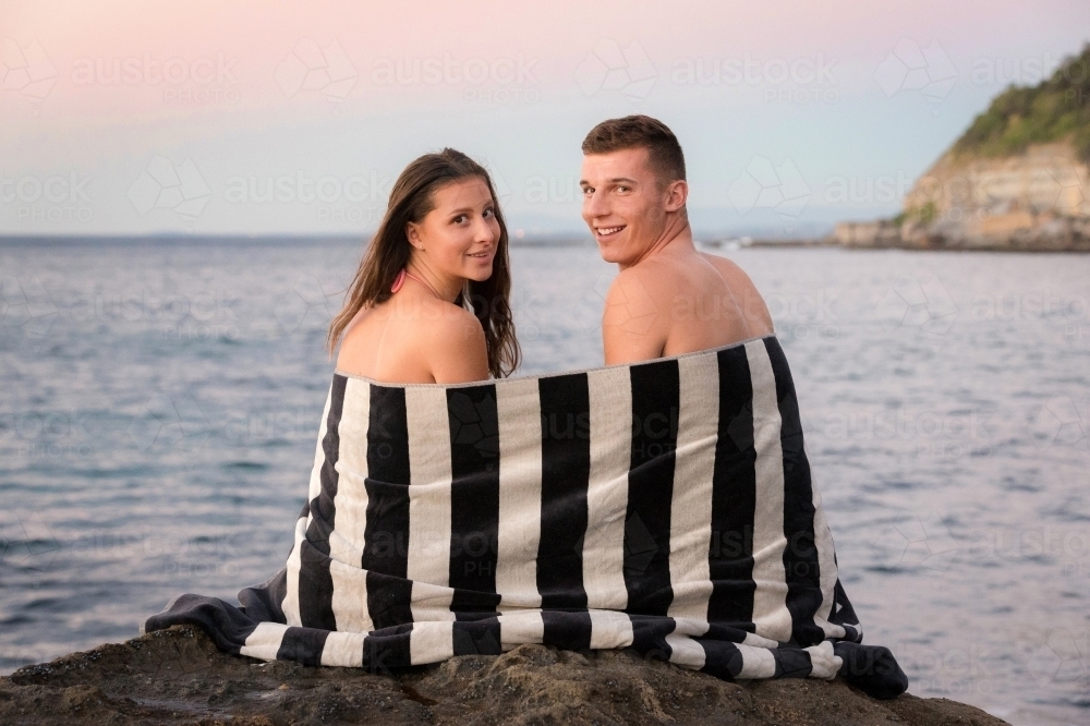 Young couple on the ocean rocks at sunrise - Australian Stock Image