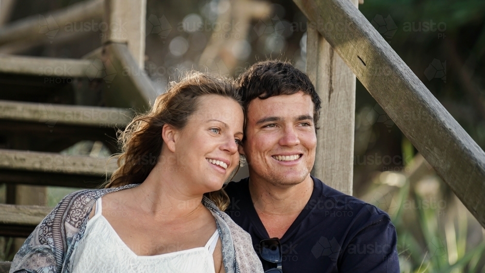 Young couple sitting on beach steps looking at ocean - Australian Stock Image