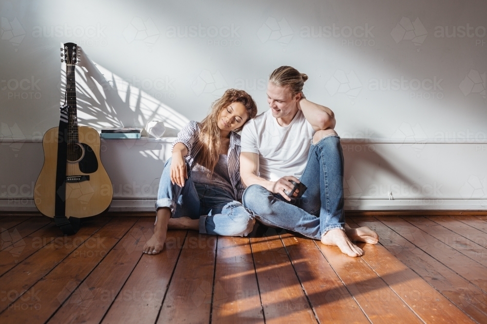 Young couple sitting on the floor of their empty new apartment - Australian Stock Image