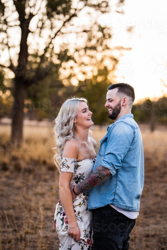 Young couple standing together in paddock laughing - Australian Stock Image