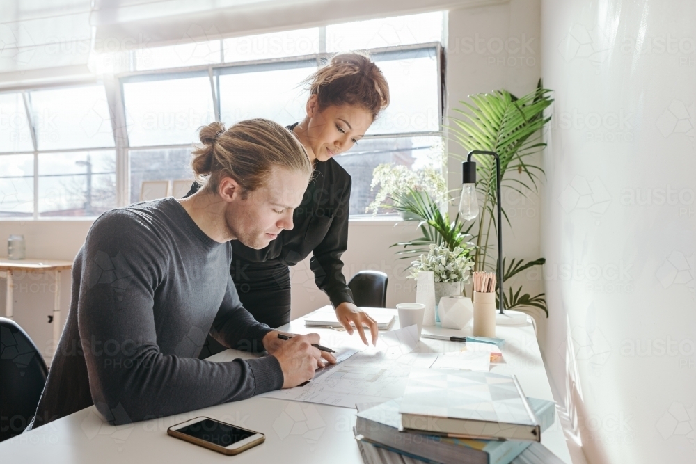 Young creatives working on a plan in a design studio - Australian Stock Image