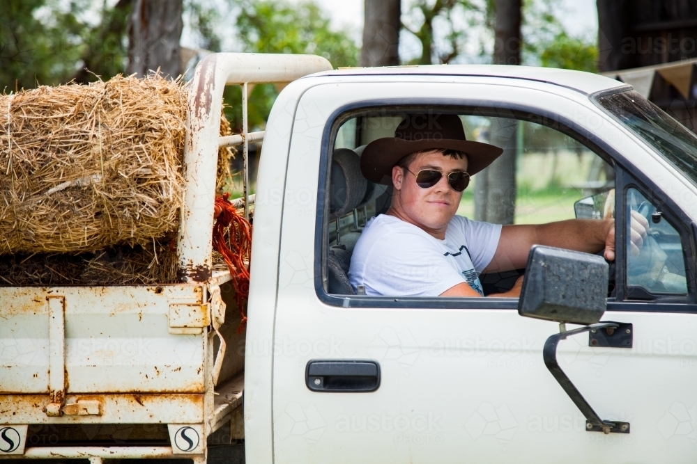 Young farmer in his 20s driving a ute in sunnies and akubra - Australian Stock Image