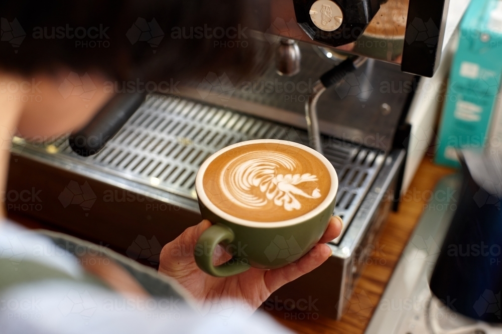 Young female barista preparing coffee with coffee machine - Australian Stock Image