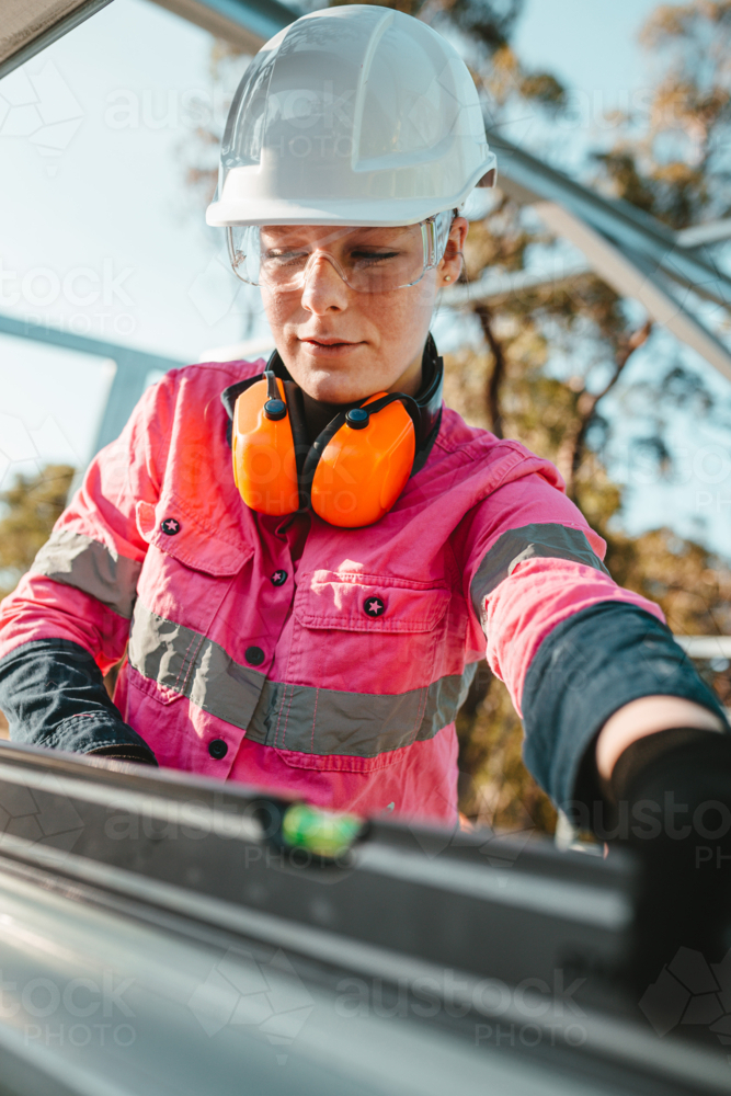 Young female construction worker using her level tool. - Australian Stock Image