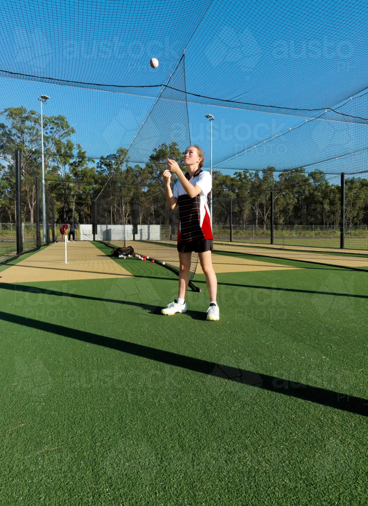 Young female cricketer practicing in the nets with cricket ball - Australian Stock Image