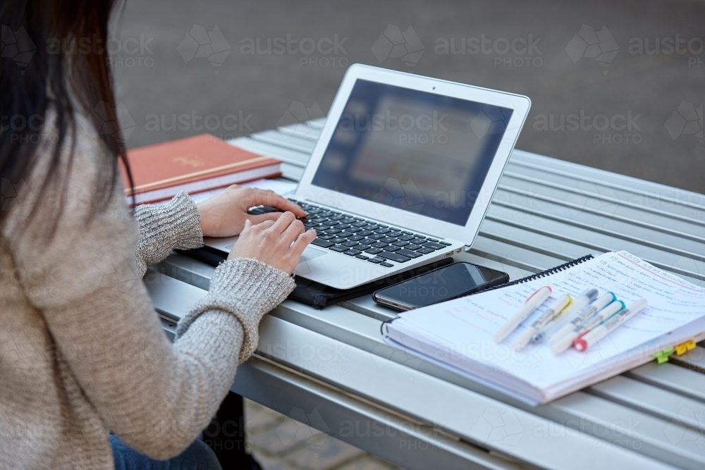 Young female student studying on her laptop outdoors - Australian Stock Image