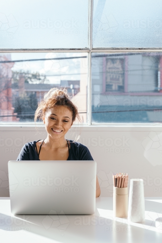 Young female working on a laptop with clear space for text - Australian Stock Image