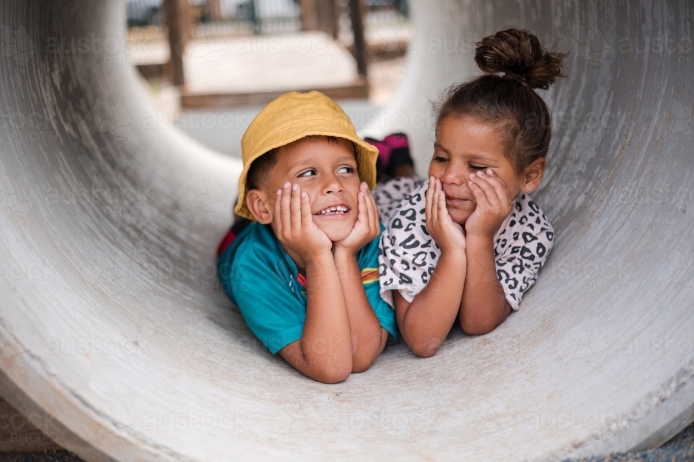 Young First Nations girl and boy playing together in a tunnel - Australian Stock Image