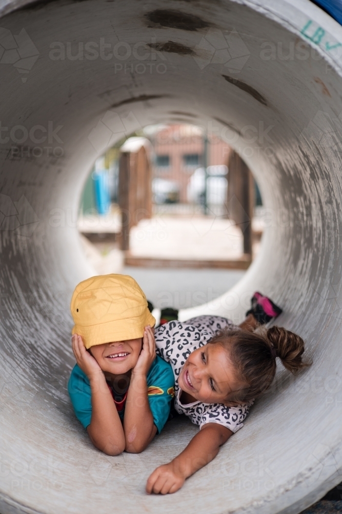 Young First Nations girl and boy playing together in a tunnel - Australian Stock Image