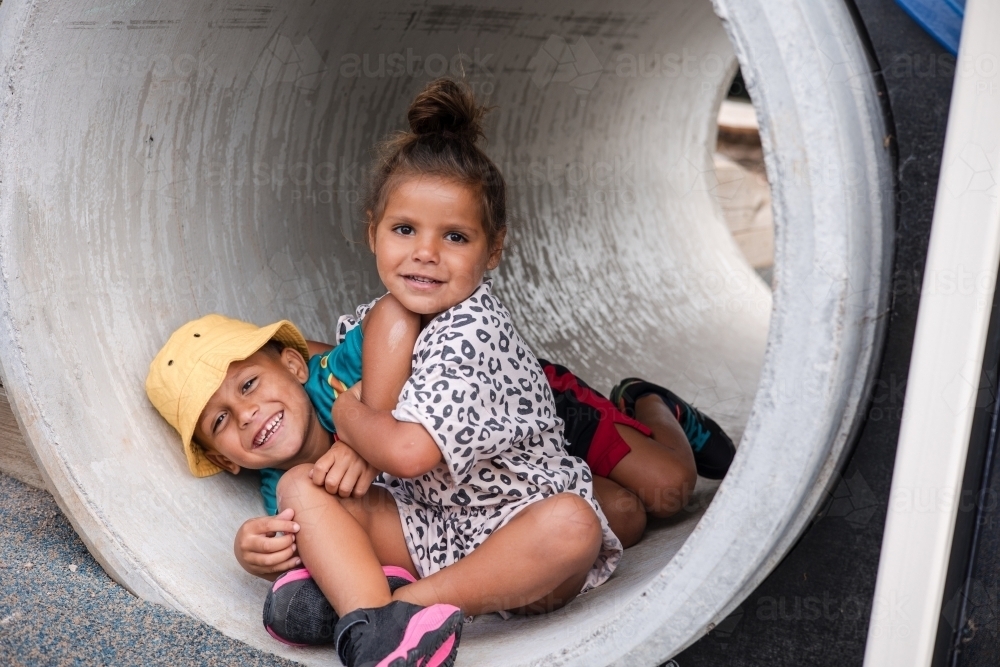 Young First Nations girl and boy playing together in a tunnel - Australian Stock Image