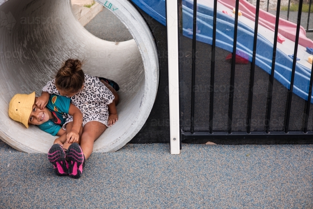 Young First Nations girl and boy playing together in a tunnel - Australian Stock Image