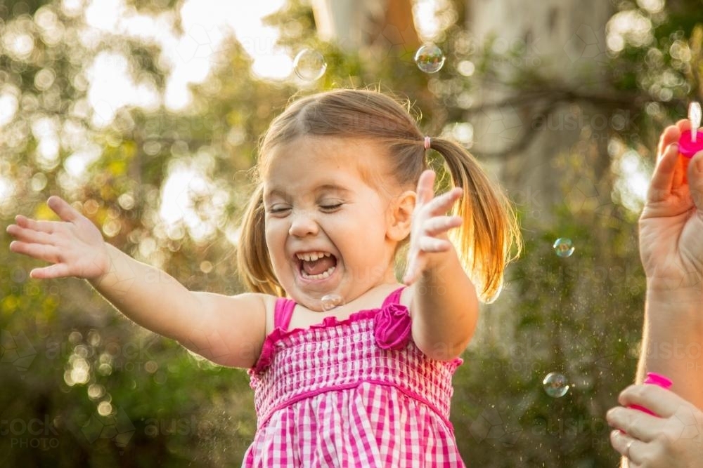 Young girl chasing bubbles outside - Australian Stock Image