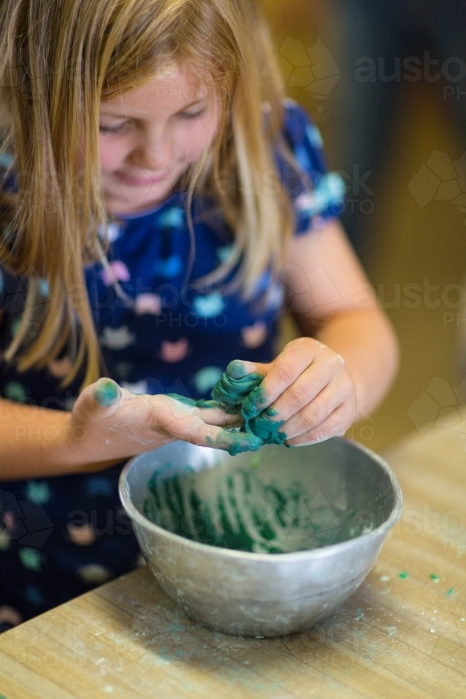 Young girl child mixing green slime in a bowl - Australian Stock Image