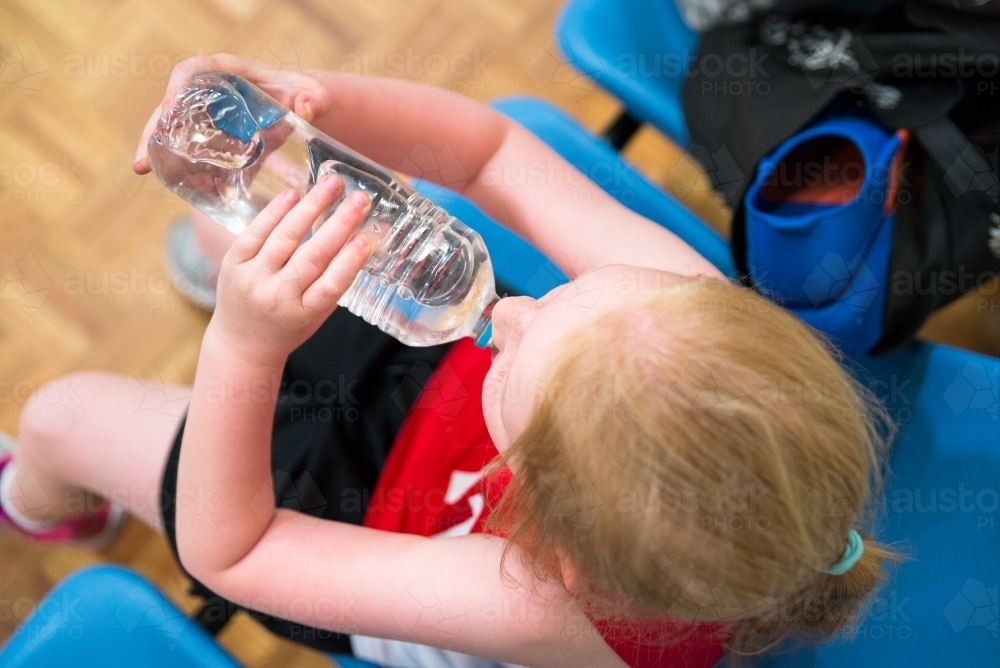 Young Girl Drinking Water On Sideline Sports Game, Top View - Australian Stock Image