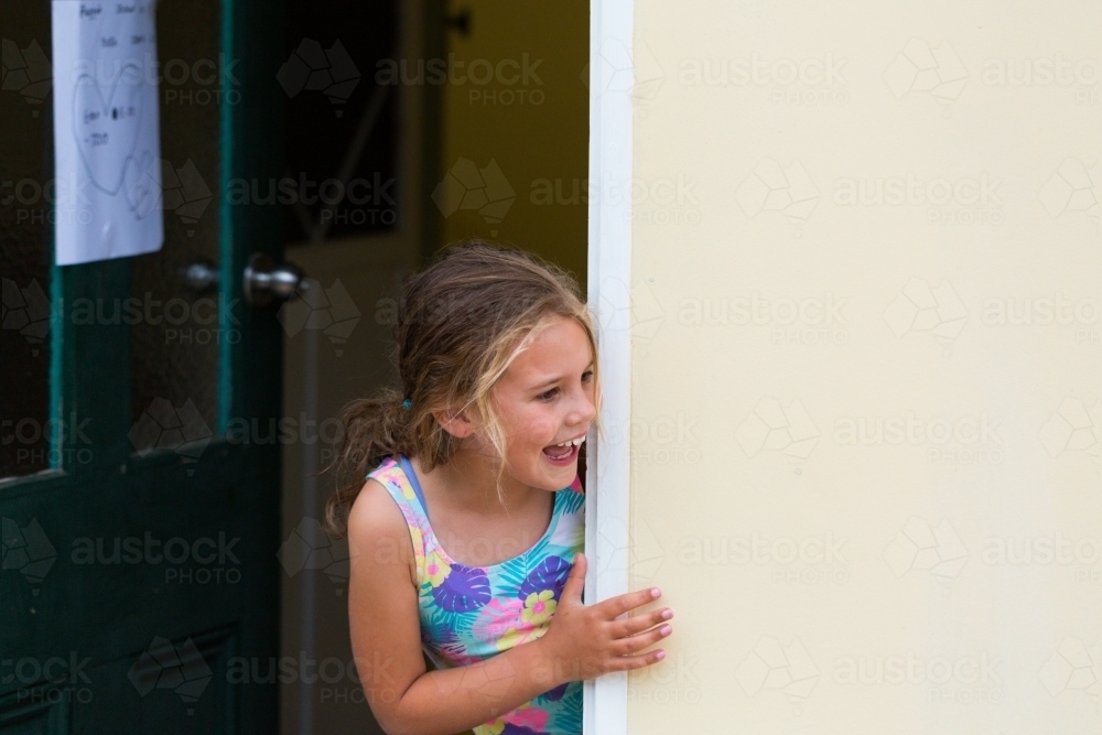 Young girl excitedly looking out of doorway - Australian Stock Image