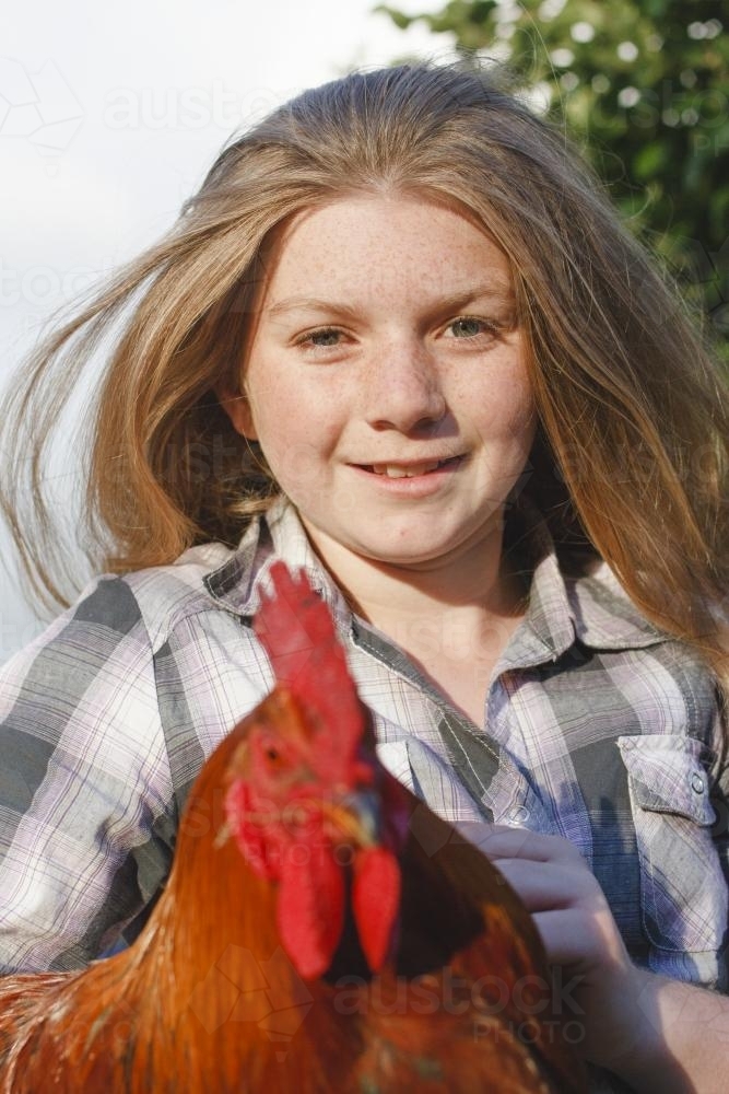 Young girl holding rooster - Australian Stock Image