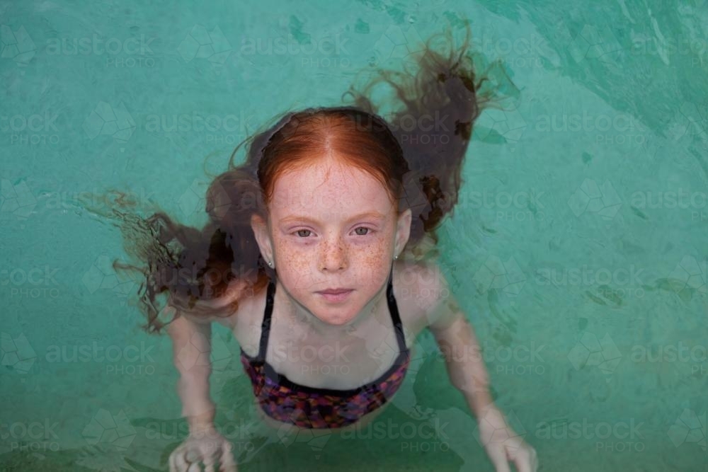 Young girl in a backyard swimming pool - Australian Stock Image