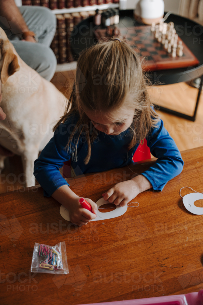 Young girl in superhero costume colouring her mask. - Australian Stock Image