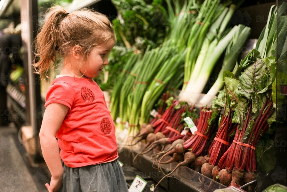 Young Girl Looking at Vegetables in Supermarket - Australian Stock Image